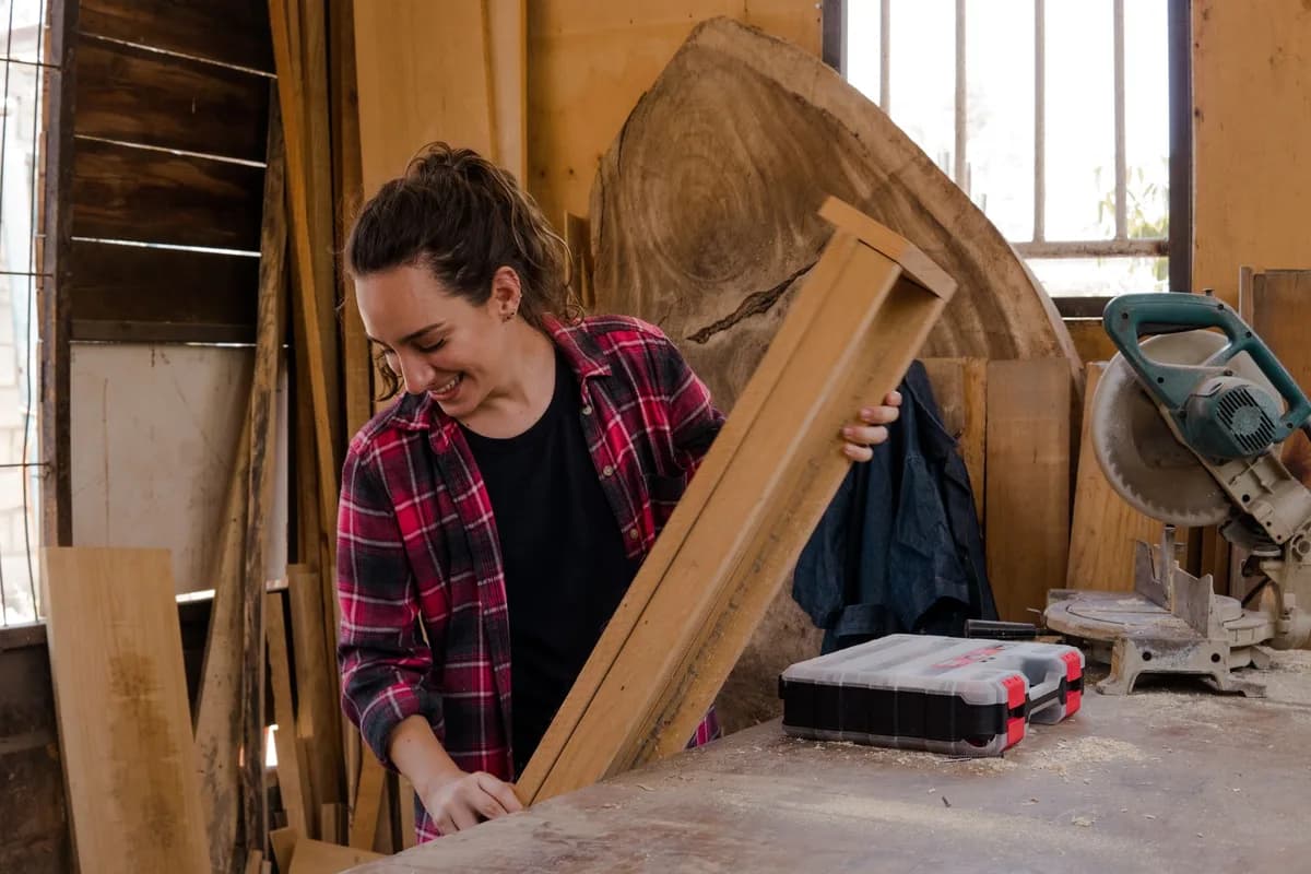 A woman carpenter handling wood in a workshop, showcasing woodworking skills and craftsmanship.