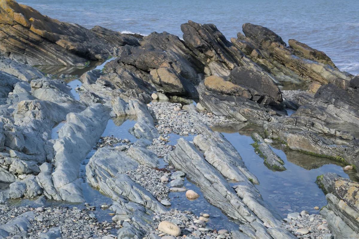 Explore the rugged rocky shoreline of Newcastle, Northern Ireland with clear ocean views.