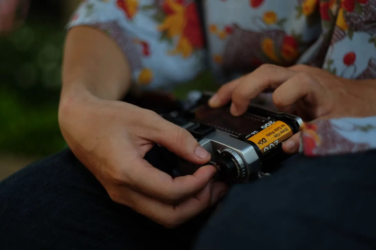 Hands carefully loading a film roll into a vintage camera, emphasizing retro photography techniques.
