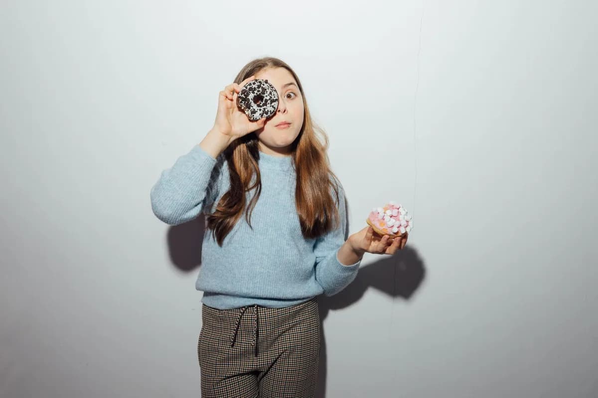 Young girl having fun with donuts, showcasing joyful expressions indoors.