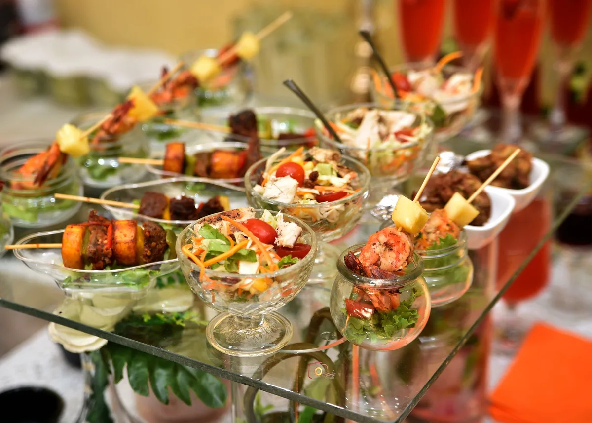 A vibrant array of appetizer skewers and salads in glassware, perfect for catering events.