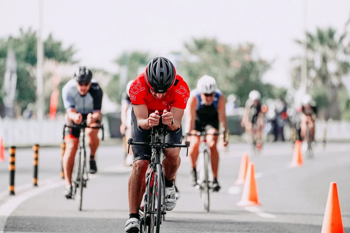 Anonymous group of male bicyclists in helmets riding bicycles on asphalt roadway with cone barriers during competition