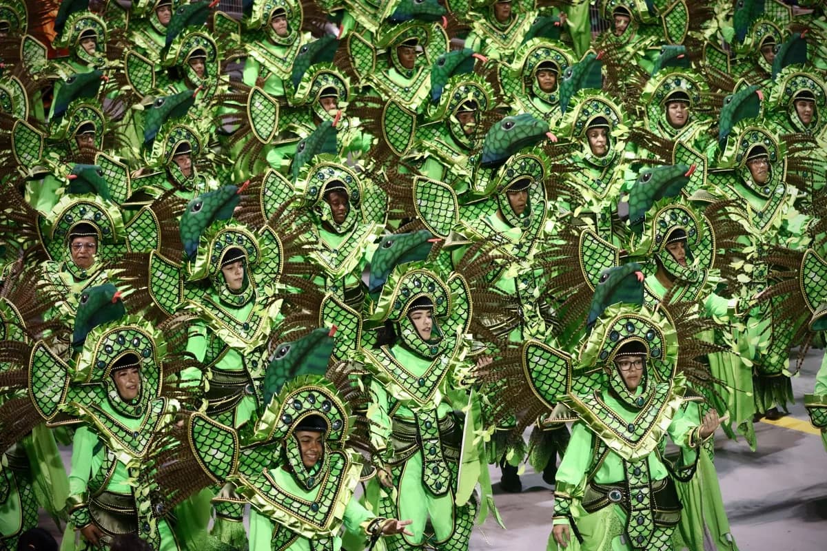 A lively carnival parade featuring colorful costumes with green and bird motifs in Brazil.