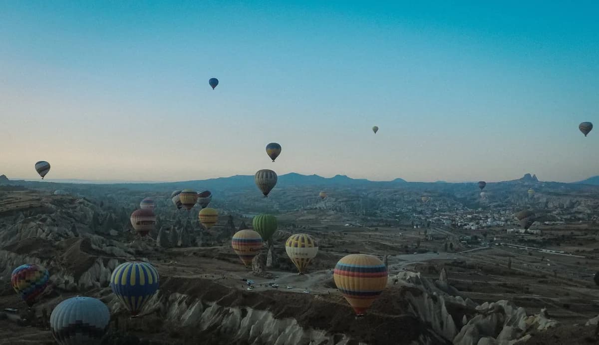 Hot air balloons soar over Cappadocia's unique landscape at dawn, capturing breathtaking views.