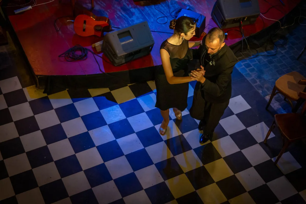 A couple gracefully dances tango in Mar del Plata, Argentina, on a checkered floor.