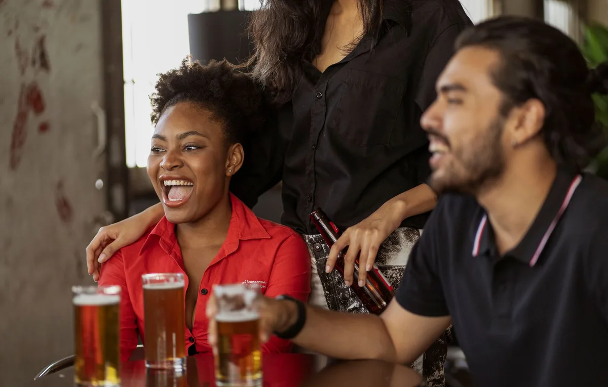 Group of friends laughing and enjoying beer together in a relaxed setting.