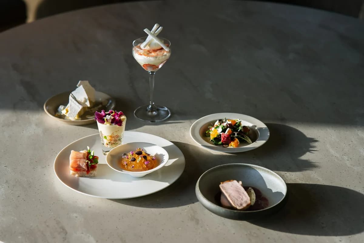Handcrafted gourmet dishes elegantly presented under natural light on a luxurious dining table.