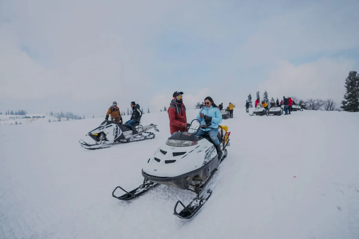 Several people enjoying a thrilling snowmobiling adventure in a winter wonderland with snowy expanses.