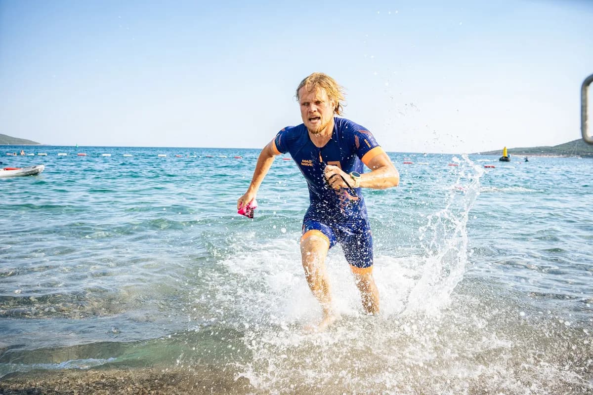 Athlete powerfully exits the water during a triathlon event, showing determination and energy.