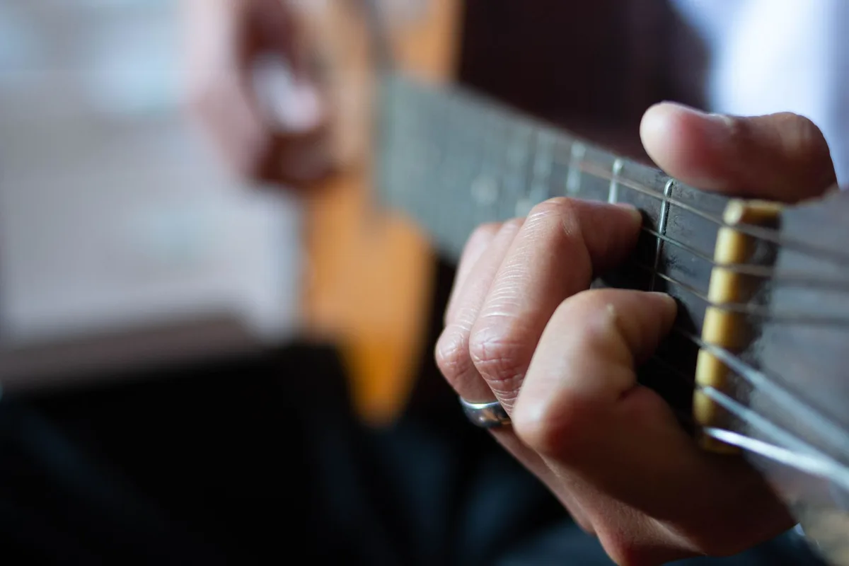 Hands strumming an acoustic guitar, showcasing musical skill and artistry.