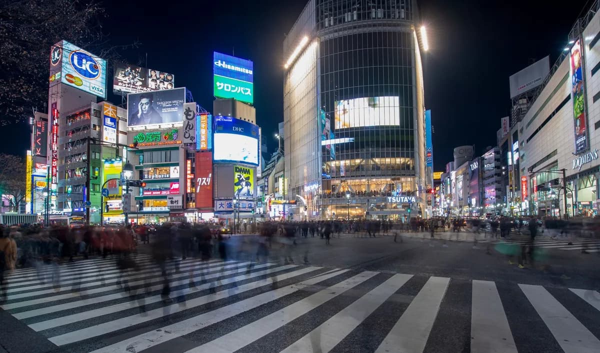 Experience the vibrant energy of Shibuya Crossing in Tokyo at night, with bustling crowds and colorful neon lights.