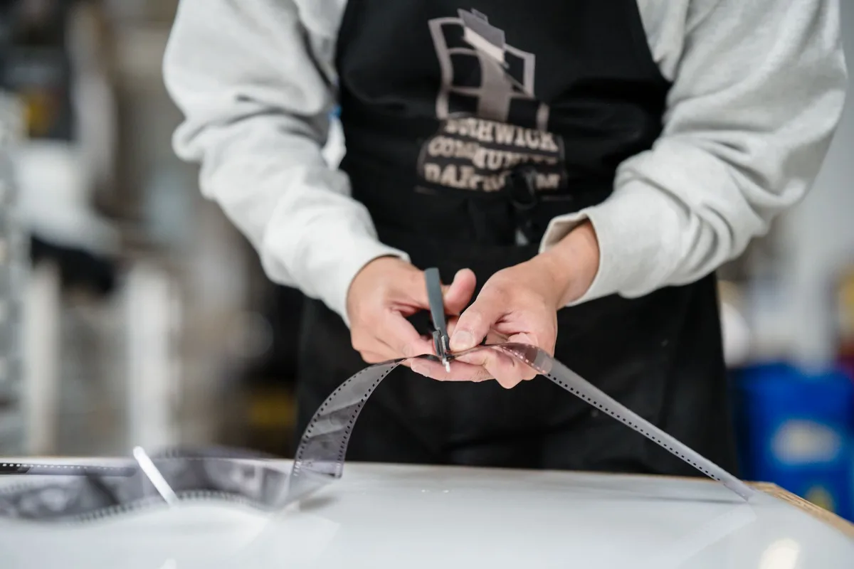A person skillfully cutting a film strip in a photography studio setting.