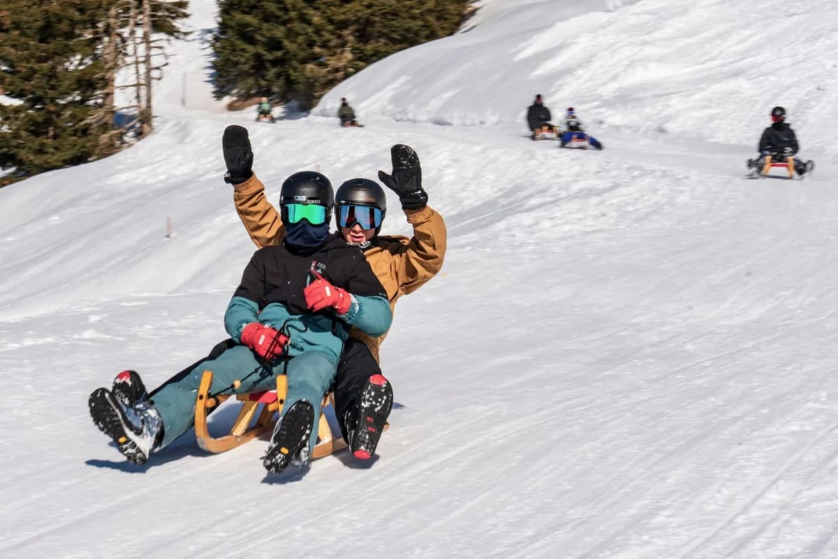 Two adults sledding down a snowy hill, enjoying winter fun and adventure.