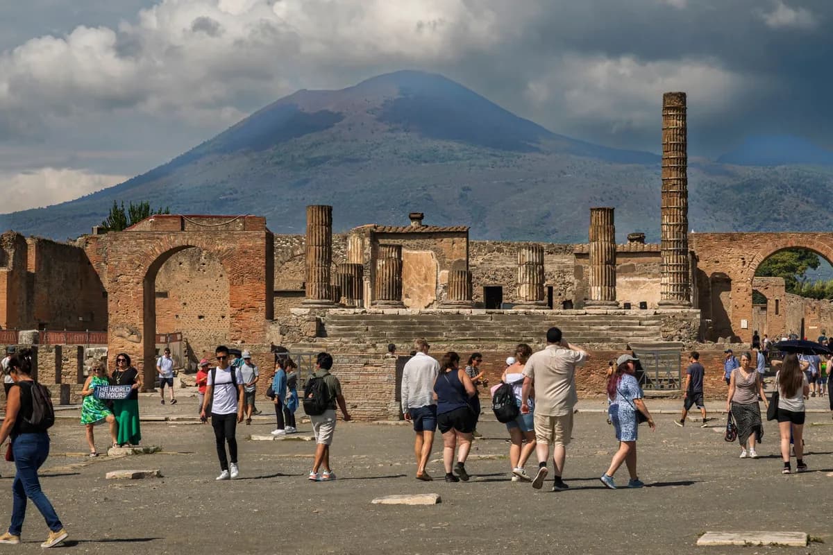 Visitors at the ancient ruins of Pompeii with Mount Vesuvius in the background.
