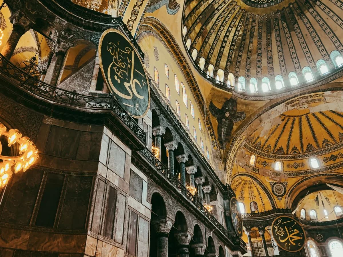 Captivating low-angle shot of Hagia Sophia's ornate dome showcasing Islamic calligraphy and detailed architecture in Istanbul.