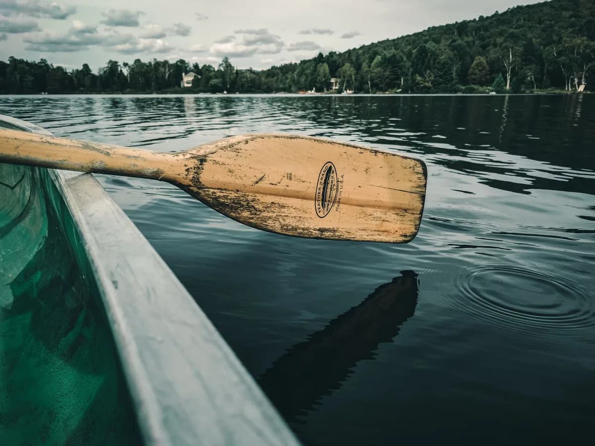 Embrace tranquility with a wooden paddle on Mont-Tremblant's pristine lake, lush forests in view.