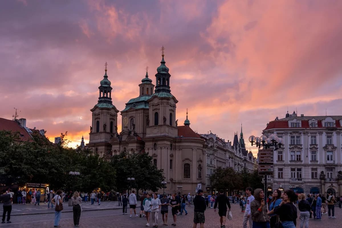 Beautiful sunset in Prague with city square, church, and people enjoying the view.