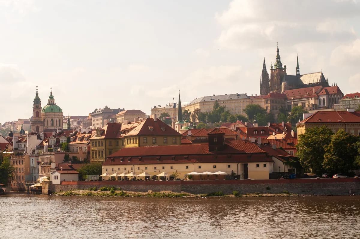 Scenic view of Prague's historic architecture along the Vltava River under a bright sky.