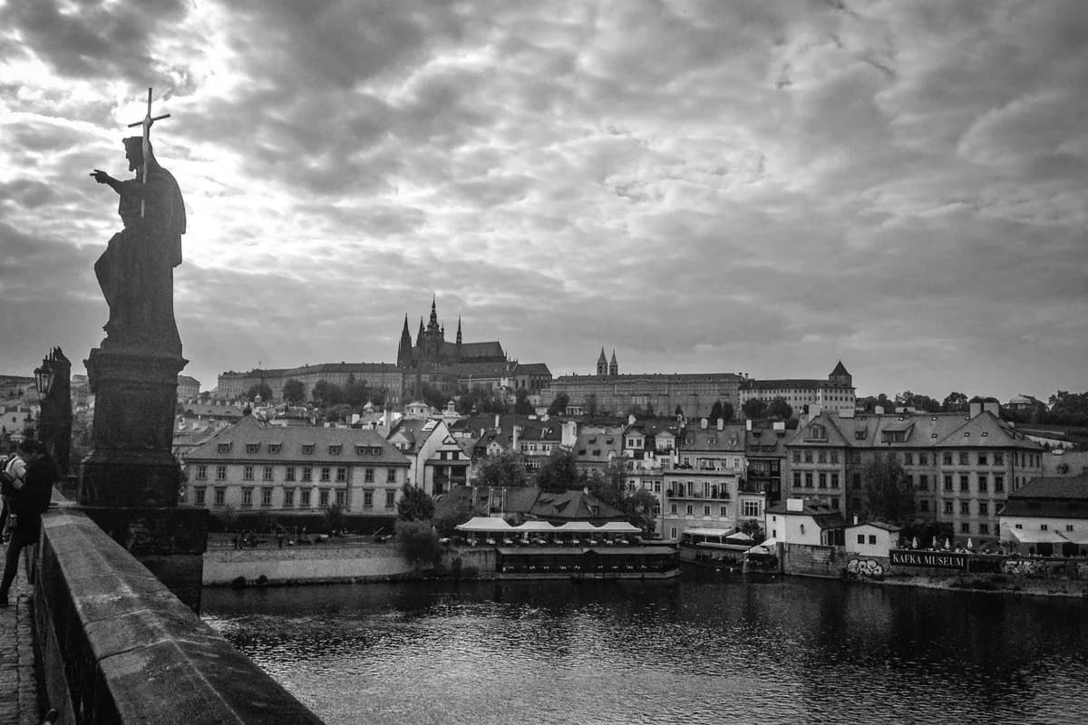 Black and white image of Prague's cityscape with Prague Castle and river.