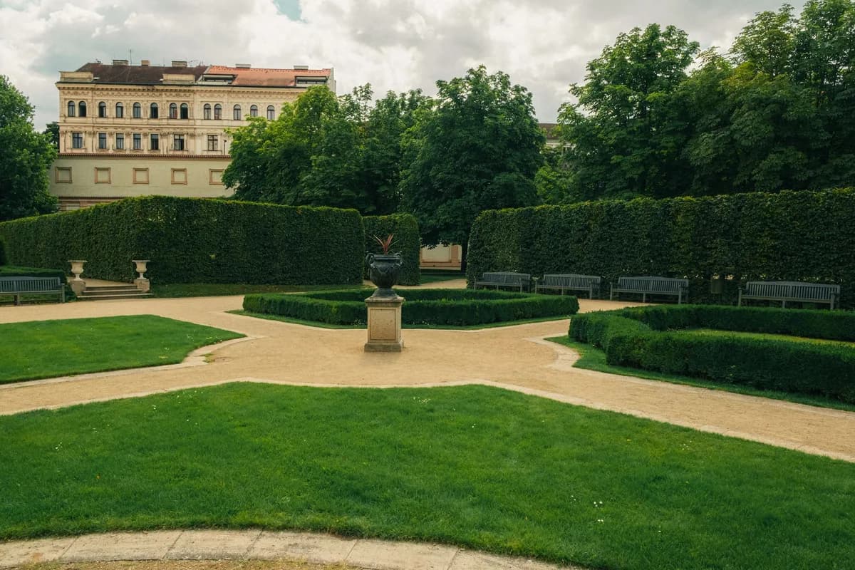 A serene formal garden with lush greenery and classical architecture in Prague.