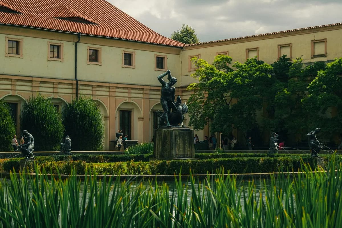 Serene landscape of Wallenstein Palace's garden with statuary and lush foliage in Prague, Czech Republic.