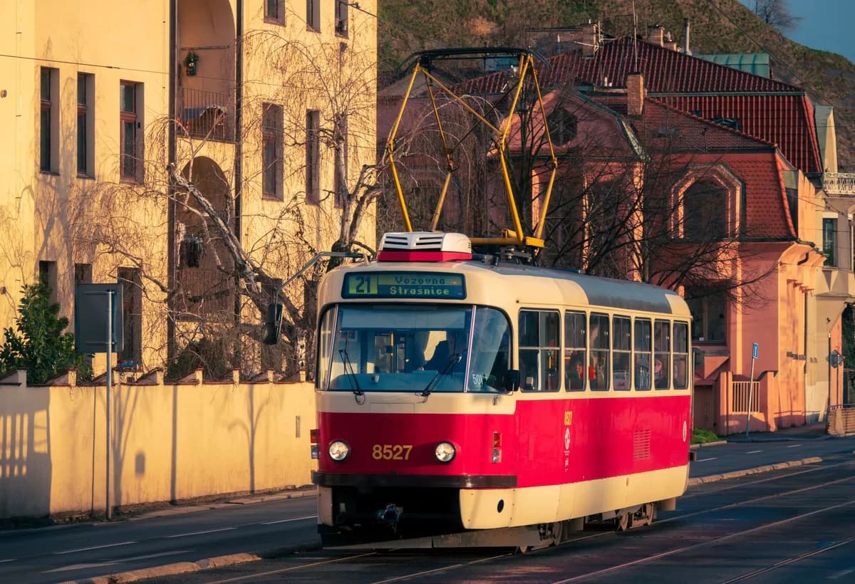Vintage red tram traveling through a sunlit street in Prague, highlighting Czechia's urban charm.